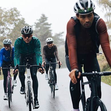 Group of cyclists riding in the rain on a road surrounded by trees
