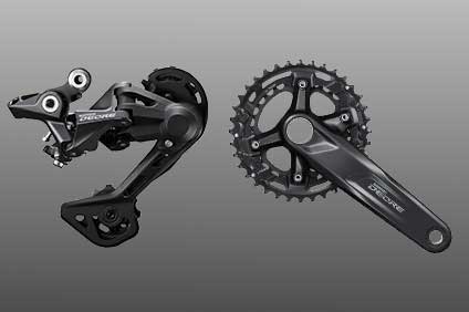 Shimano Deore bike parts including derailleur and crankset on gray background