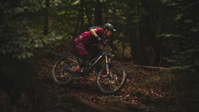 Mountain biker riding through a forest trail in protective gear