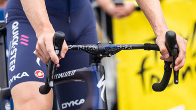 Cyclist's hands on handlebars, wearing Quick-Step team uniform and riding a Specialized bike