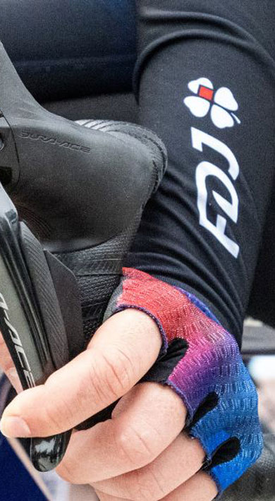 Close-up of cyclists' hands on handlebars, wearing gloves and FDJ branded clothing.