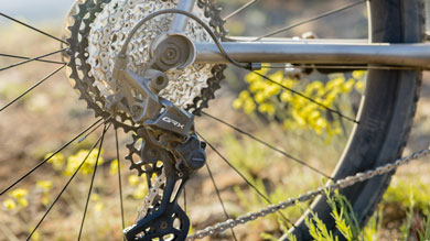 Close-up of a Shimano GRX rear derailleur on a bicycle in a natural setting