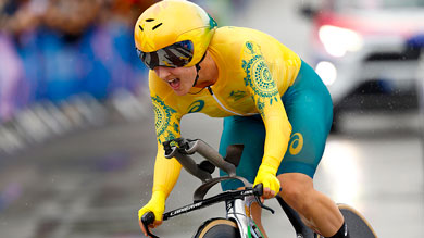 Radsportlerin in gelb-grünem Dress fährt Fahrrad bei einem Rennen an einem regnerischen Tag