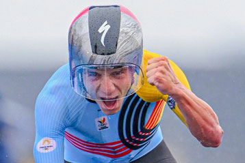 Radsportler mit Helm reckt bei einem Rennen begeistert die geballte Faust empor