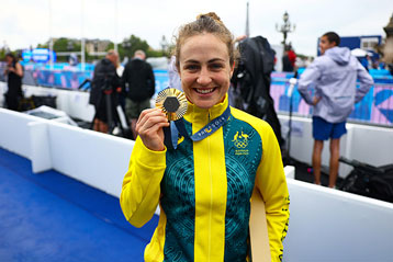Athletin lacht und hält bei einer Veranstaltung eine Goldmedaille