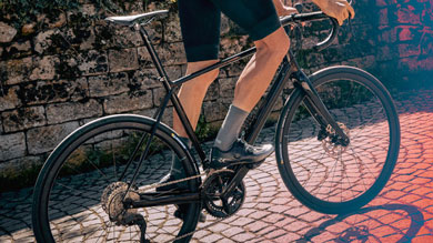 Cyclist riding a black road bike on a cobblestone path