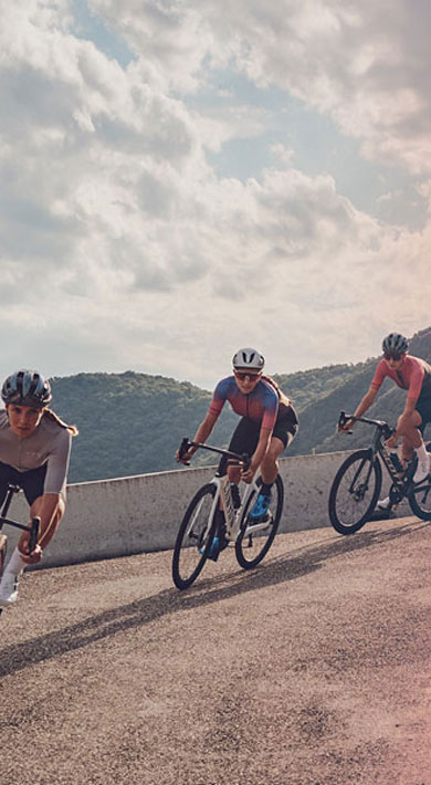 Three cyclists riding on a mountain road during a cloudy day