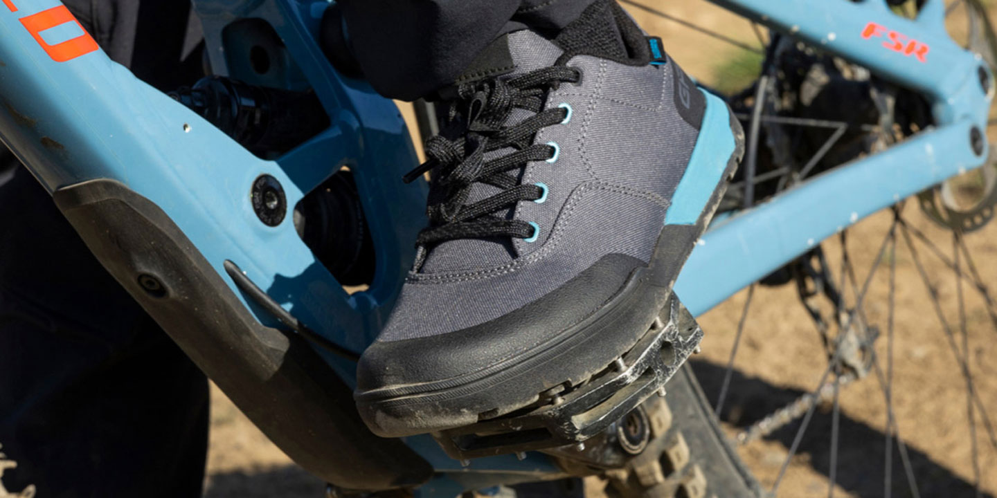 Close-up of a person wearing cycling shoes on a blue mountain bike pedal