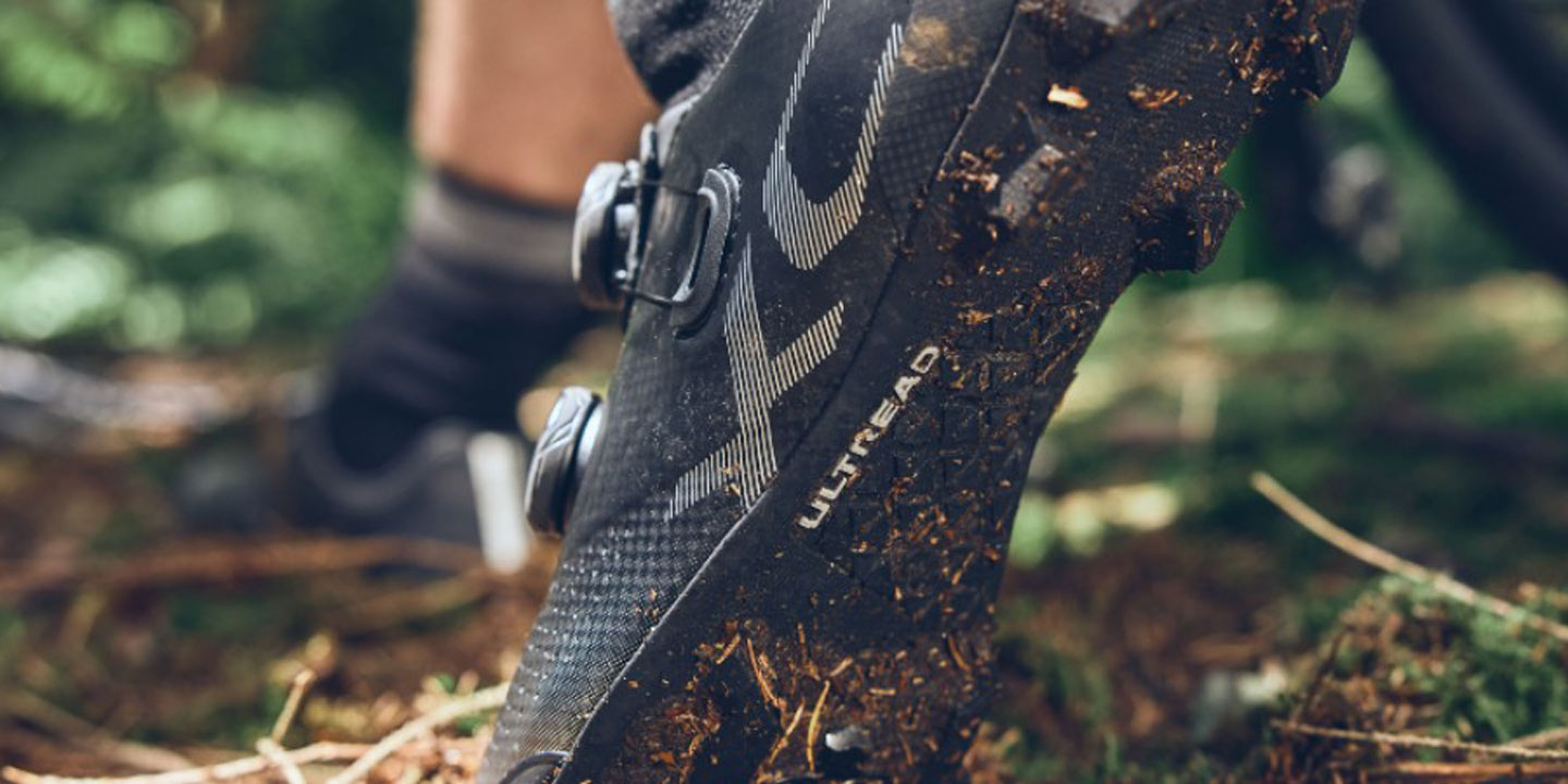 Close-up of muddy mountain bike shoe in forest setting